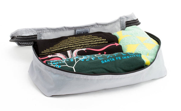 An open Northwest Sky (light grey) Aether Aeronaut 30 Small Packing Cube holding four shirts.